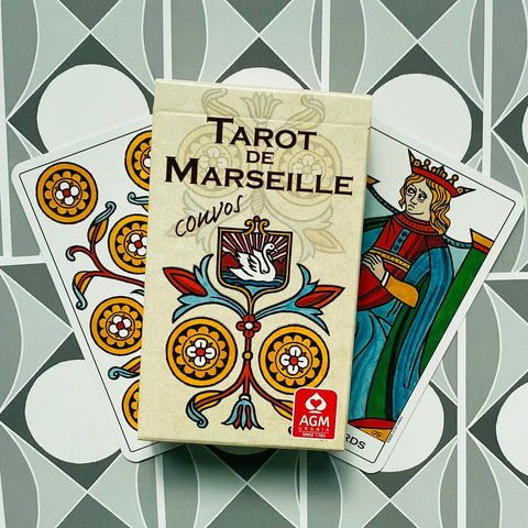 Tarot de Marseille kortų rinkinys su kremine dėže ir AGM ženklu, parodytas iš priekio ant atverstų kortų