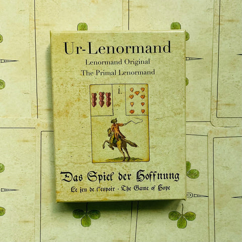 Lenormand kortų rinkinys Ur‑Lenormand — kreminė senovinė dėžutė su jojančio vyro kortele ant lapelių fono