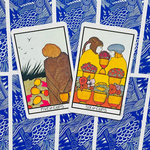 Tarot kortos Rider‑Waite stiliaus: dvi atverstos kortos (Penki taurės ir Šeši taurės) ant mėlynos raštuotos nugarėlės, galerijos variantas