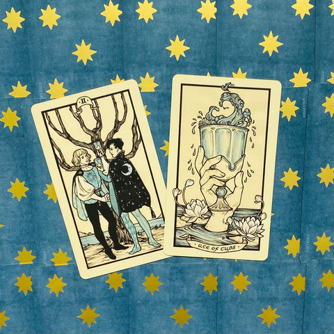 tarot kortos — dvi atverstos kortos (Ace of Cups ir Two of Cups) ant mėlyno fono su geltonomis žvaigždėmis