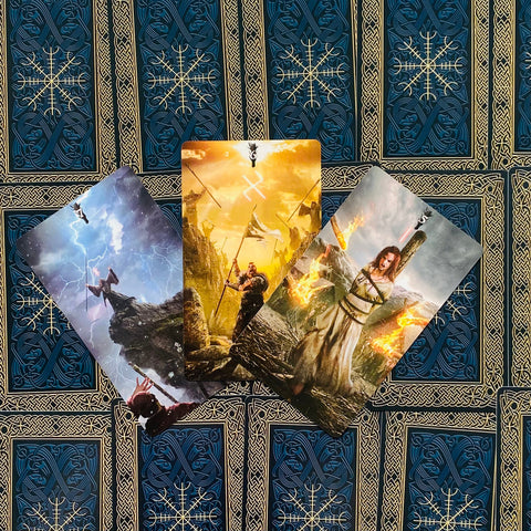 tarot kortos vikingų tematikos komplektas, trys atvertos kortos – centrinė auksinė karo scena ant mėlyno ir auksinio nugarėlių fono