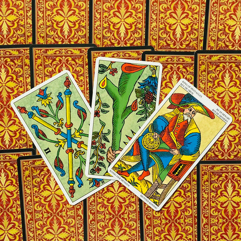 Tarot kortos Marseille stiliaus, ryškios priekinės kortos (Karalius monetų, lazdos, stiebas) ant raudono ornamentuoto nugarėlių fono