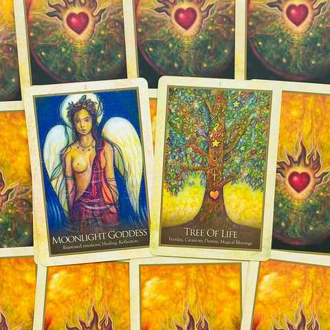 tarot kortos atverstos: Moonlight Goddess ir Tree of Life kortos priešakyje, spalvingi simboliai ir auksinis fonas