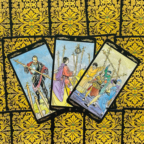 Tarot kortos – trys atvertos Lazdų rūšies kortos (5, 6, 7) su ryškiais piešiniais ant prabangių auksinių‑juodų nugarėlių