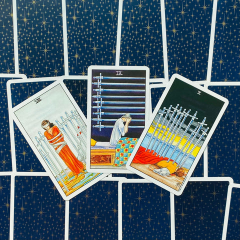 Tarot kortos Rider–Waite stiliaus, mėlyna žvaigždėta nugarėlė, trijų kardų išdėstymas (VIII, IX, X), persidengiančios kortos, pabrėžta skausmo tema