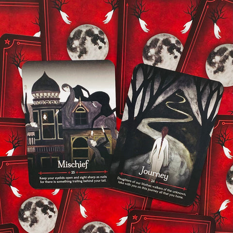 Tarot kortos su raudonomis mėnulio nugarėlėmis, atverstos Mischief ir Journey kortos su tamsiu, gotišku iliustratyviu dizainu
