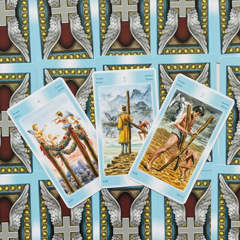 Tarot kortos komplektas su šviesiai mėlynomis kraštinėmis, trys atverstos Lazdų rūšies kortos centre rodo skirtingas interpretacijas
