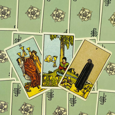 Tarot kortos — trijų Taurių kortų išklotinė su klasikiniu Rider–Waite piešiniu ant šviesiai žalių nugarėlių