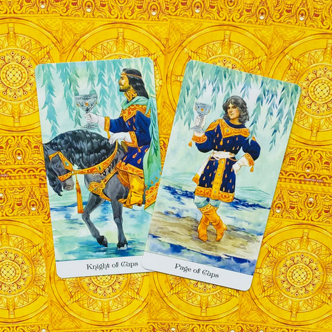 Tarot kortos su Riteriu ir Puslapiu Taurės variantu, mėlynos iliustracijos ant ryškaus geltono ornamentuoto fono