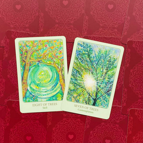 Tarot kortos su atviromis „Eight of Trees“ ir „Seven of Trees“ kortomis — žali medžių piešiniai prieš raudonus nugarėlių raštus