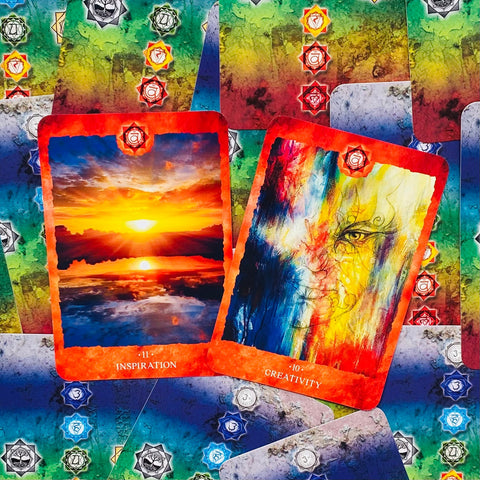Tarot kortos su ryškiomis oranžinėmis kraštinėmis, dvi atverstos kortos Inspiration ir Creativity ant marginto čakrų fono