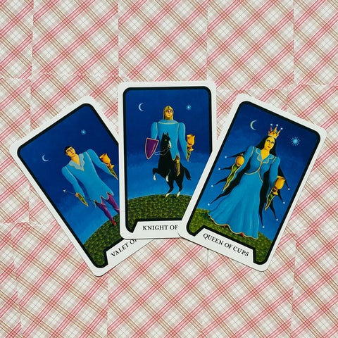 tarot kortos mėlynu teminiu dizainu — trys taurų rūšies kortos (valetas, riteris, karalienė), išdėstytos ant raštuoto fono