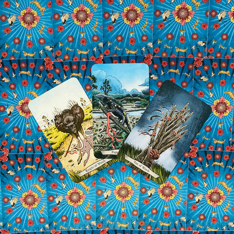 tarot kortos — trijų kortų išdėstymas (Riteris, Puslapė, Dešimt lazdų) ant mėlynos gėlių nugarėlės, šiek tiek kampu