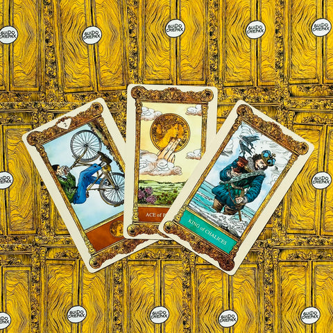 Tarot kortos Guido Crepax, aukso geltonos nugarėlės ir trijų atvirų kortų (tarp jų Monetų tūzas, Taurių karalius) priekinis dizainas