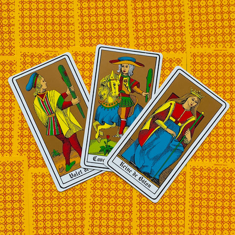 Tarot kortos Marseilio stiliaus – trys lazdų rūšies kortos (pusininkas, riteris, karalienė) ant geltono raštuoto fono