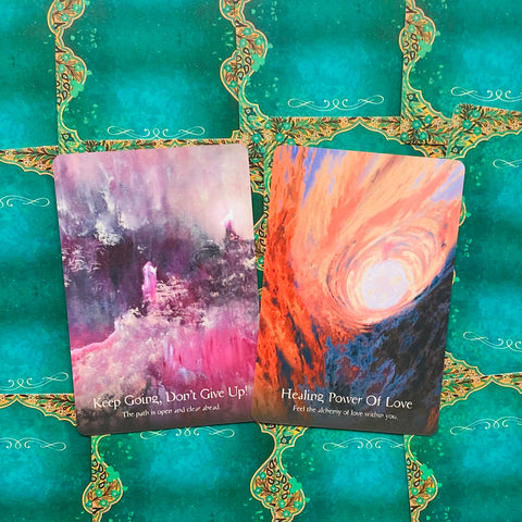 Tarot kortos su dviem variantais: violetinė‑rožinė Keep Going ir oranžinė Healing Power, parodytos ant žalio fono