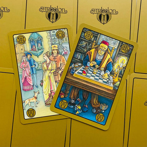 Tarot kortos Symbolon su auksiniu fonu, dvi atverstos spalvotos iliustruotos kortos matomos iš viršaus