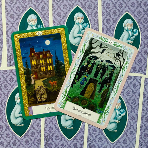 tarot kortos, dvi atviros kortos — naktinė vila su auksiniu rėmu ir laidotuvių scena su žalios–rožinės kortos rėmu, skirtos aiškinimui