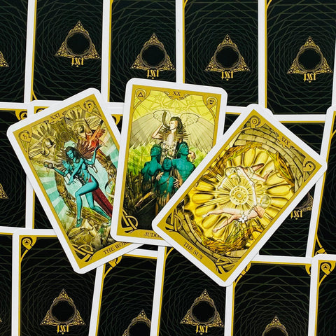 Tarot kortos su auksinėmis kraštinėmis, trys atverstos didžiųjų arkanių kortos (Pasaulis, Teismas, Saulė) ant juodų nugarėlių