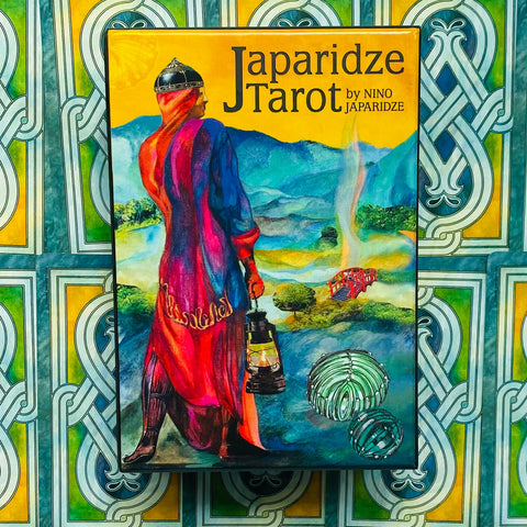 Japaridze tarot kortos, spalvinga dėžutė su keliautojo figūra laikant žibintą, priekinis vaizdas ant dekoratyvaus fono