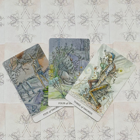 tarot kortos — trys „Kardų“ kortos (3, 4, 5) su akvareliniais iliustracijomis, kampu išdėstytos ant rausvo ornamentuoto nugarėlių fono, variantas su matomu kortų numeriavimu