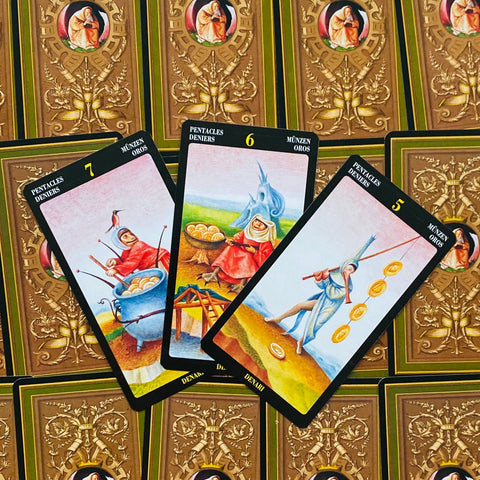taro kortos Pentacles komplektas, trys išklotos kortos su spalvotais iliustracijomis ir dekoratyviomis rudos nugarėlės