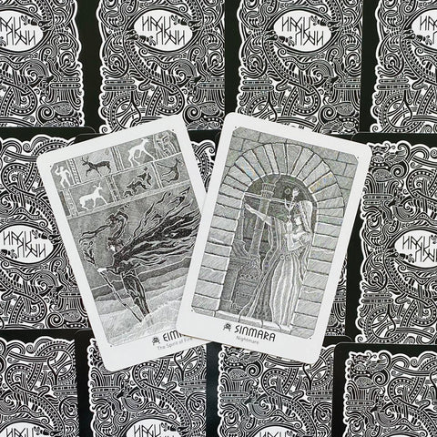 Tarot kortos juoda‑balta kolekcija, dvi atvertos kortos (Sinmara ir Eimyrja) ant raštuotų nugarėlių fono