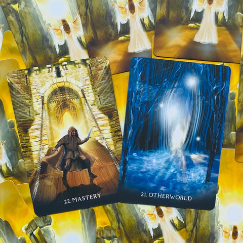 Tarot kortos atvertos: "Mastery" su aukso pilies vartais ir "Otherworld" mėlyname mistiniame miške, fotografuota iš viršaus