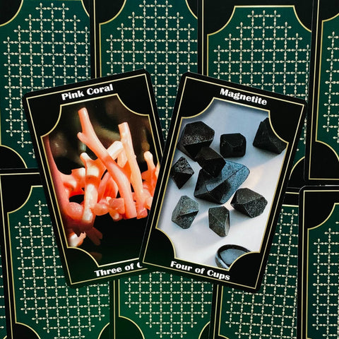 Tarot kortos su dviem priekiais: rožinė Pink Coral ir juoda Magnetite korta ant žalių užpakalių, artimas planas