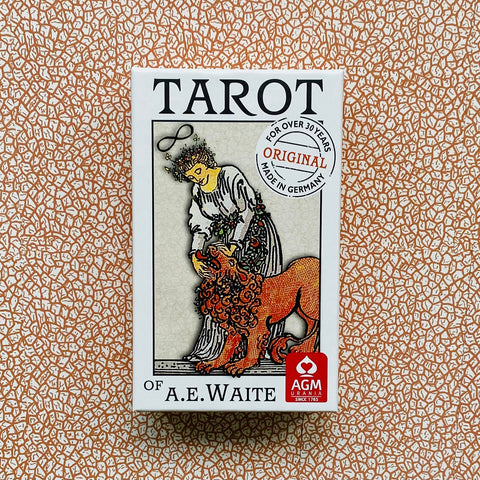 Tarot kortos A.E. Waite baltame dėkle su moters ir liūto iliustracija, originaliu „Made in Germany“ lipduku ir ornamentuotu fonu