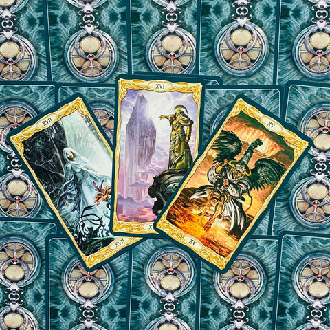 Tarot kortos — trijų kortų išklotinė su turkio nugarėlėmis ir aukso rėmeliais, matomos detalių iliustracijos pažymėtos XVI–XVII numeriais