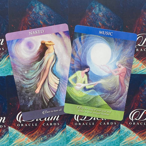 Orakulo kortos Dream Oracle — dvi atverstos kortos (Naked violetinė ir Music mėlyna) kampu, matomos priekio iliustracijos su moterimis