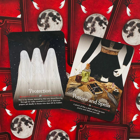 tarot kortos rinkinys su raudonu mėnulio nugarėlių dizainu, dvi atverstos kortos parodytos iš viršaus (Protection ir Potions and Spells), unikalus magiškas variantas