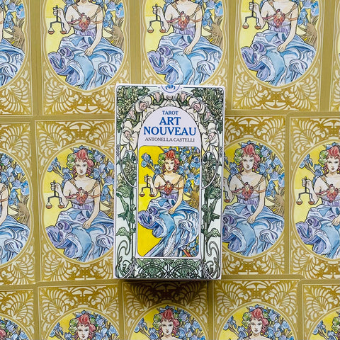Tarot kortos Art Nouveau dėžutė centre ant aukso ornamentuoto fono, su moters atvaizdu, laikant svarstykles