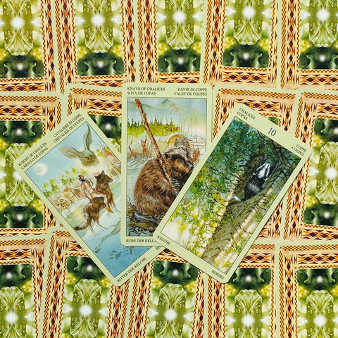 Tarot kortos — trys atverstos taurės kortos su gyvūnų iliustracijomis ant žalių raštuotų nugarėlių