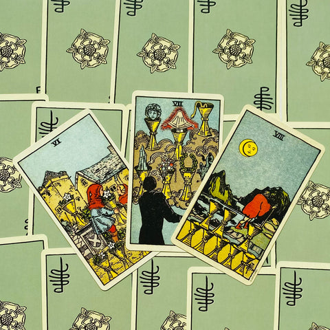 Tarot kortos Rider–Waite stiliaus, žaliomis nugarėlėmis, fanuotos trys taurės (VI–VIII) parodytos artimame plane