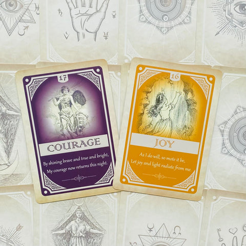 Orakulų kortos, dvi atverstos — violetinė Courage ir oranžinė Joy ant ornamentuoto foninio rašto, produktų demonstracija
