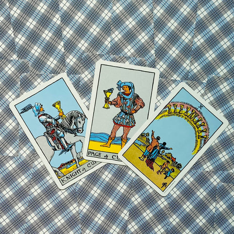 Tarot kortos trijų kortų komplektas — Riteris, Puslapis ir Dešimt taurų ant mėlyno, tinkuoto raštuoto fono, parduotuvei skirtas kampinis kadravimas