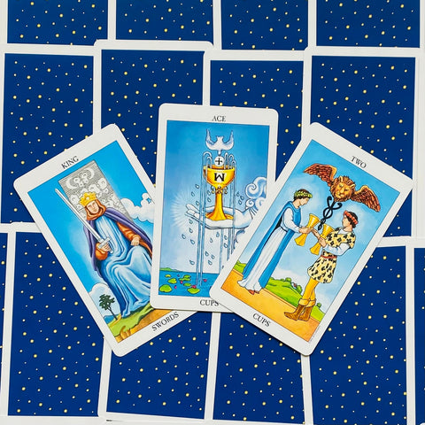 Tarot kortos Rider‑Waite stiliaus, mėlynos nugarėlės su geltonomis žvaigždėmis, trijų kortų išklotinė centrinė Ace of Cups