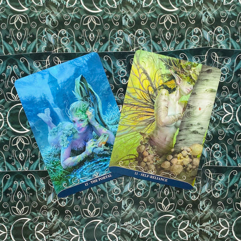 tarot kortos su dviem iliustruotomis kortelėmis — mėlyna „The Portal“ ir žalia „Self‑Reliance“, išdėstytos ant dekoratyvios tamsiai žalios fono medžiagos