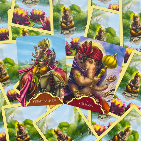 Orakulo kortos su Ganesha iliustracijomis — dvi atviros kortos (Steadfastness, Decision) ryškiais violetiniais ir auksiniais tonais