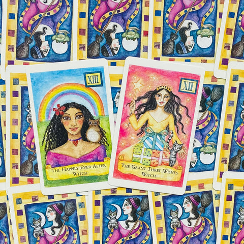 Tarot kortos su spalvingais priekiniais piešiniais: pelėda prie vaivorykštės ir raganė su dovanomis bei kate, fone daug nugarėlių