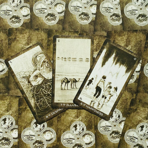 Tarot kortos trijų kortų išdėstyme: gyvatės, kupranugarių ir vaikų piešiniai matomi prie detalios ornamentuotos nugarėlės