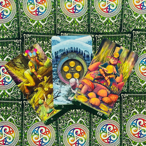 tarot kortos su žaliu ornamentuotu nugarėliu, trys atvertos Pentaklų kortos su ryškiomis, spalvingomis iliustracijomis