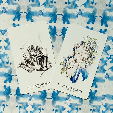 Tarot kortos – dvi kortos iš serijos (Four of Swords ir Five of Swords) ant mėlyno akvarelės rašto fono, plokščiai išdėstytos