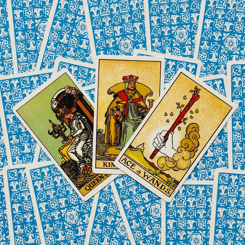 tarot kortos Rider–Waite rinkinys: trys atverstos kortos (Ace of Wands, karalius ir karalienė) ant mėlynos raštuotos nugarėlės