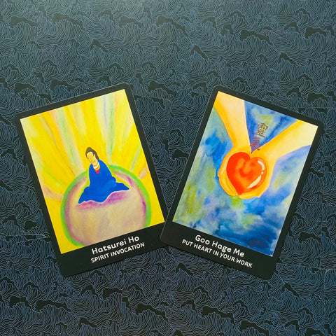 Tarot kortos — dvi spalvingos akvarelinės kortos (meditacija ir rankos su širdimi), nuotrauka iš viršaus ant tamsaus raštuoto fono