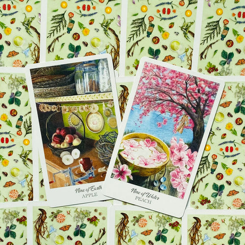 Tarot kortos, dvi iliustruotos kortos (Nine of Earth Apple ir Nine of Water Peach) ant žalio gėlių fono, iš priekio