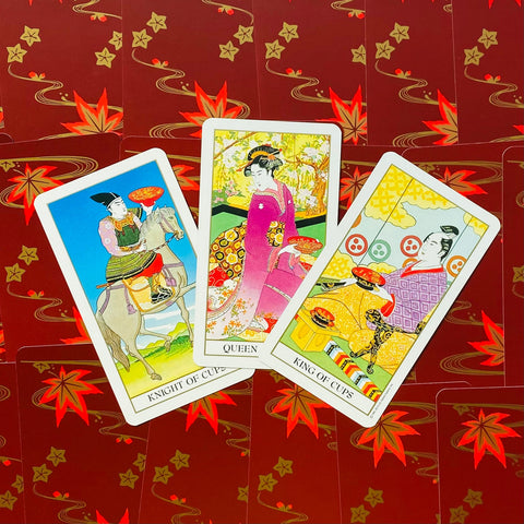Tarot kortos japonų stiliaus: trys taurų rūmų kortos (Riteris, Karalienė, Karalius) ant raudono lapų nugarėlio, rodoma dizaino variacija