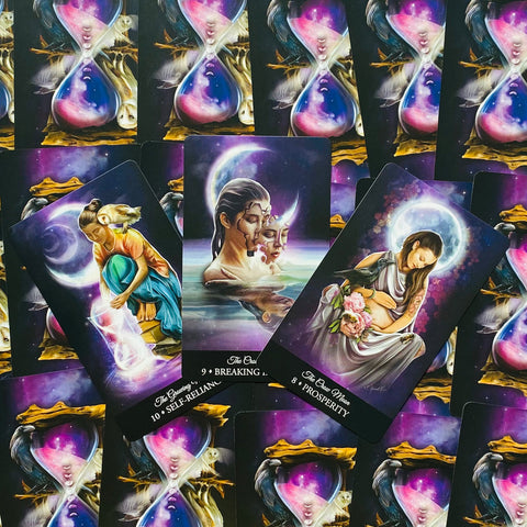 Tarot kortos su kosminėmis iliustracijomis, trys išskirtinės kortos priekyje virš fono su smėlio laikrodžiais